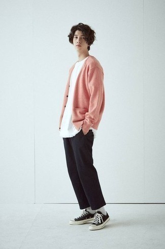 rosa Strickjacke, weißes T-Shirt mit einem Rundhalsausschnitt, schwarze Chinohose, schwarze und weiße Segeltuch niedrige Sneakers für Herren