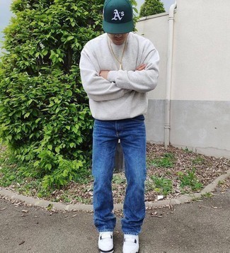 graues Sweatshirt, dunkelblaue Jeans, weiße Segeltuch niedrige Sneakers, dunkelgrüne bedruckte Baseballkappe für Herren