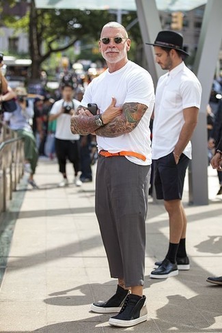 Nick Wooster trägt weißes T-Shirt mit einem Rundhalsausschnitt, graue Leinen Anzughose, schwarze hohe Sneakers aus Leder, orange Ledergürtel