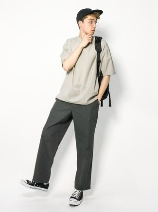 graues T-Shirt mit einem Rundhalsausschnitt, dunkelgrüne Chinohose, schwarze und weiße Segeltuch niedrige Sneakers, schwarzer Segeltuch Rucksack für Herren
