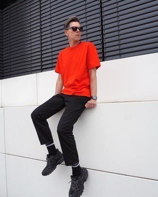 orange T-Shirt mit einem Rundhalsausschnitt, schwarze Chinohose, schwarze Sportschuhe, dunkelbraune Sonnenbrille für Herren