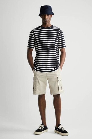 dunkelblaues und weißes horizontal gestreiftes T-Shirt mit einem Rundhalsausschnitt, hellbeige Shorts, schwarze und weiße Segeltuch niedrige Sneakers, dunkelblauer Fischerhut für Herren
