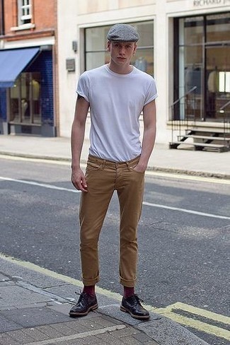 weißes T-Shirt mit einem Rundhalsausschnitt, beige Jeans, schwarze Leder Derby Schuhe, graue Schiebermütze für Herren