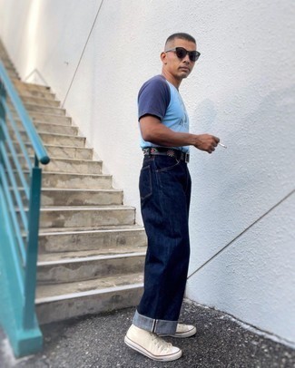 Herren Outfits 2021: Erwägen Sie das Tragen von einem hellblauen bedruckten T-Shirt mit einem Rundhalsausschnitt und dunkelblauen Jeans für einen entspannten Wochenend-Look. Hellbeige hohe Sneakers aus Segeltuch sind eine ideale Wahl, um dieses Outfit zu vervollständigen.