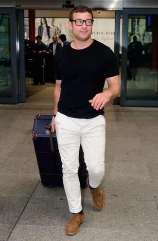 Dermot O'Leary trägt schwarzes T-Shirt mit einem Rundhalsausschnitt, weiße Chinohose, braune Wildleder Derby Schuhe, schwarze Socke