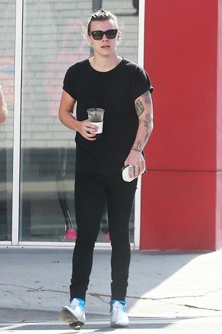 Harry Styles trägt schwarzes T-Shirt mit einem Rundhalsausschnitt, schwarze enge Jeans, graue Chelsea-Stiefel aus Leder, schwarze Sonnenbrille