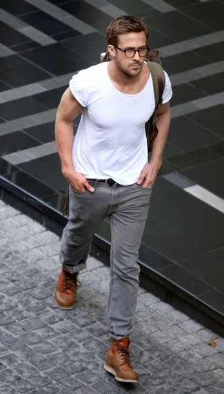 Ryan Gosling trägt weißes T-Shirt mit einem Rundhalsausschnitt, graue Jeans, beige Lederarbeitsstiefel, olivgrüner Rucksack