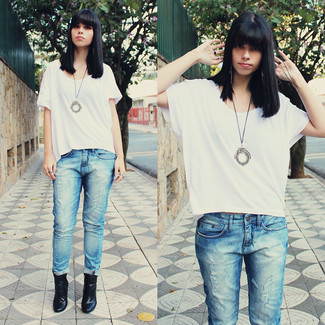 weißes T-Shirt mit einem Rundhalsausschnitt, hellblaue Jeans mit Destroyed-Effekten, schwarze Leder Stiefeletten, silberner Anhänger für Damen