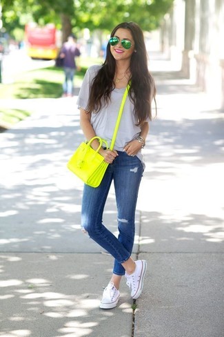 graues T-Shirt mit einem V-Ausschnitt, blaue enge Jeans mit Destroyed-Effekten, weiße Segeltuch niedrige Sneakers, gelbgrüne Leder Umhängetasche für Damen