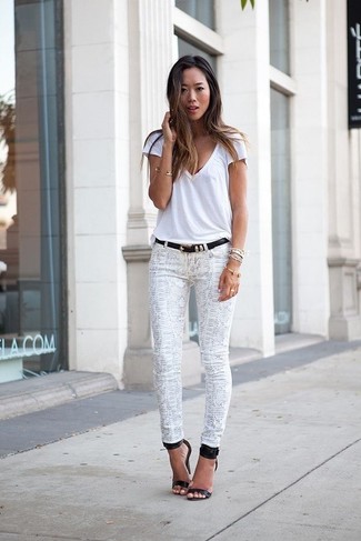 weißes T-Shirt mit einem V-Ausschnitt, weiße enge Jeans mit Schlangenmuster, schwarze Leder Sandaletten, schwarzer Ledergürtel für Damen