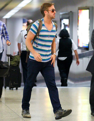 Ryan Gosling trägt weißes und blaues horizontal gestreiftes T-Shirt mit einem V-Ausschnitt, dunkelblaue Jeans, olivgrüne Lederfreizeitstiefel, olivgrüner Segeltuch Rucksack