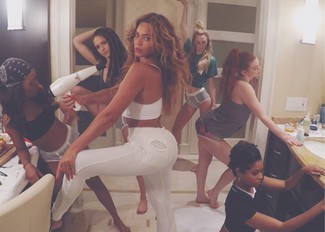 Beyonce trägt weißes kurzes Oberteil, weiße enge Jeans mit Destroyed-Effekten