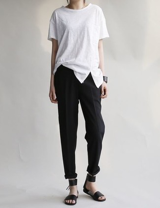 weißes T-Shirt mit einem Rundhalsausschnitt, schwarze Karottenhose, schwarze flache Sandalen aus Leder für Damen