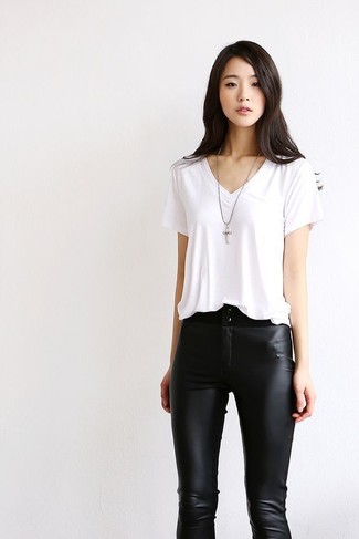 weißes T-Shirt mit einem V-Ausschnitt, schwarze enge Hose aus Leder, silberner Anhänger für Damen
