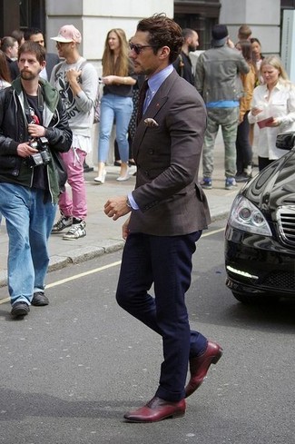 David Gandy trägt dunkelbraunes Zweireiher-Sakko, hellblaues Businesshemd, dunkelblaue Chinohose, dunkelrote Leder Oxford Schuhe